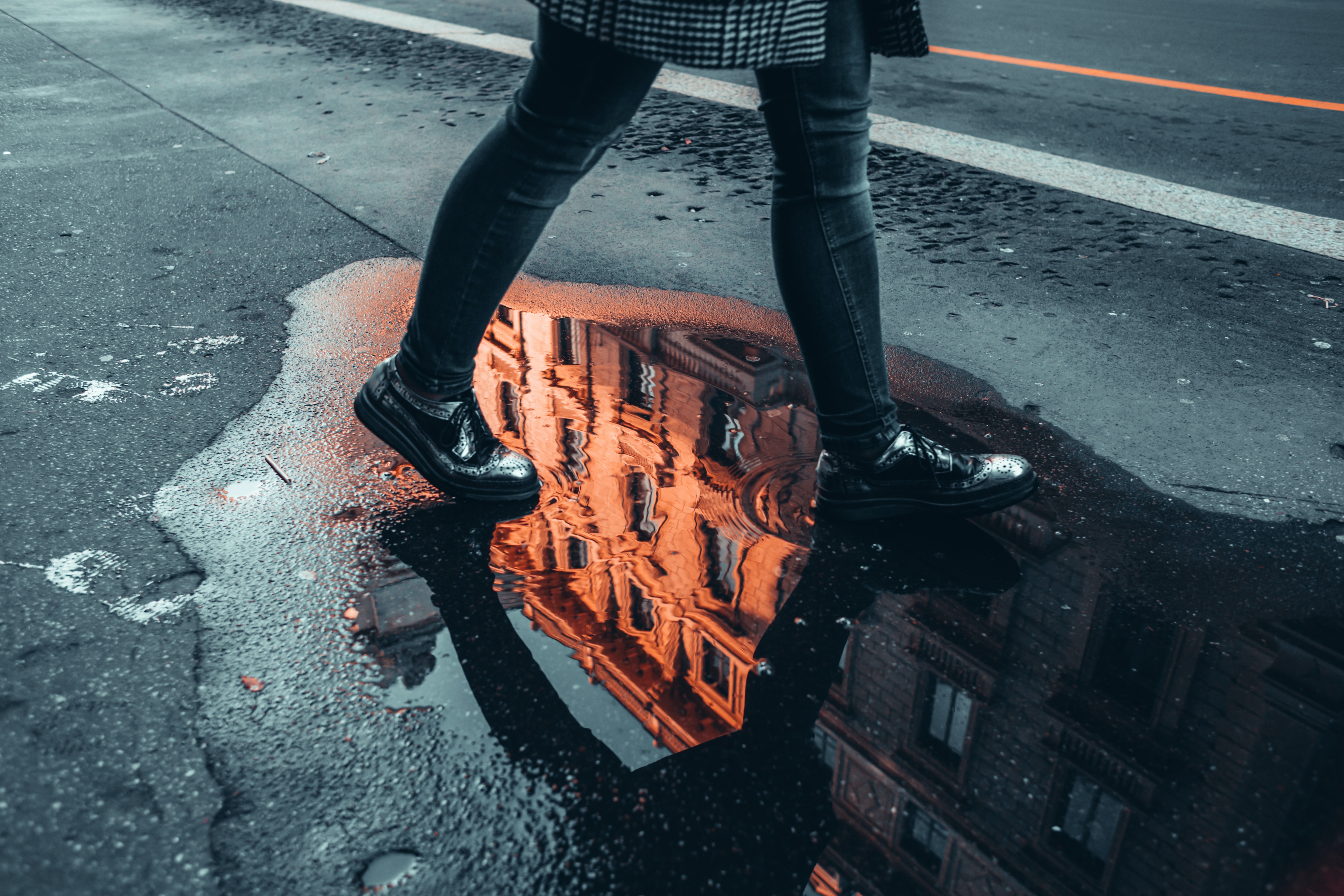 A person walking through a puddle on a city street